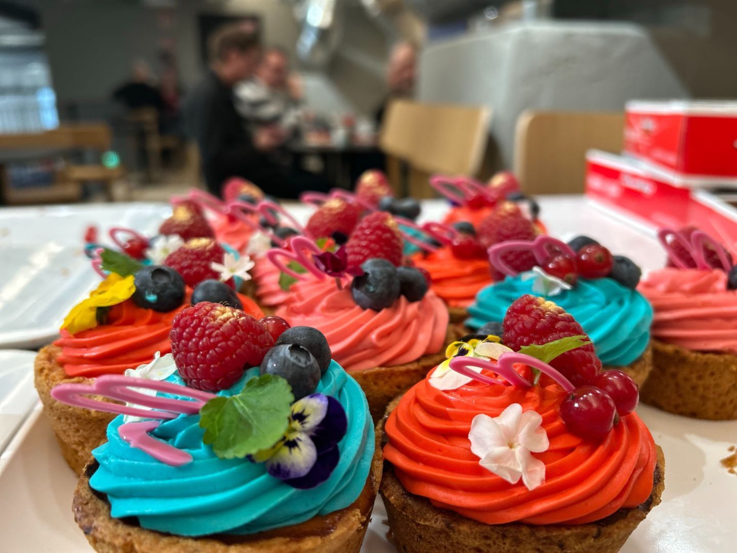 Tarjottimella eri värisellä kermavaahdolla kuorrutettuja muffineja. Osa punaisia, osa sinisiä.
Red and blue cupcakes.