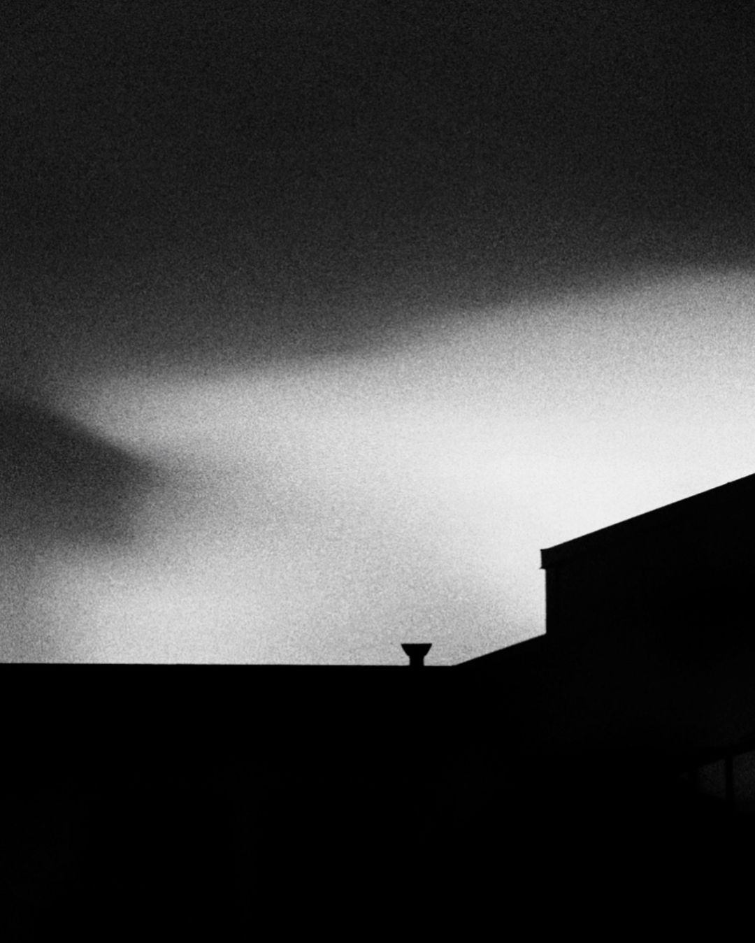Clouds in the sky, dark building on foreground.