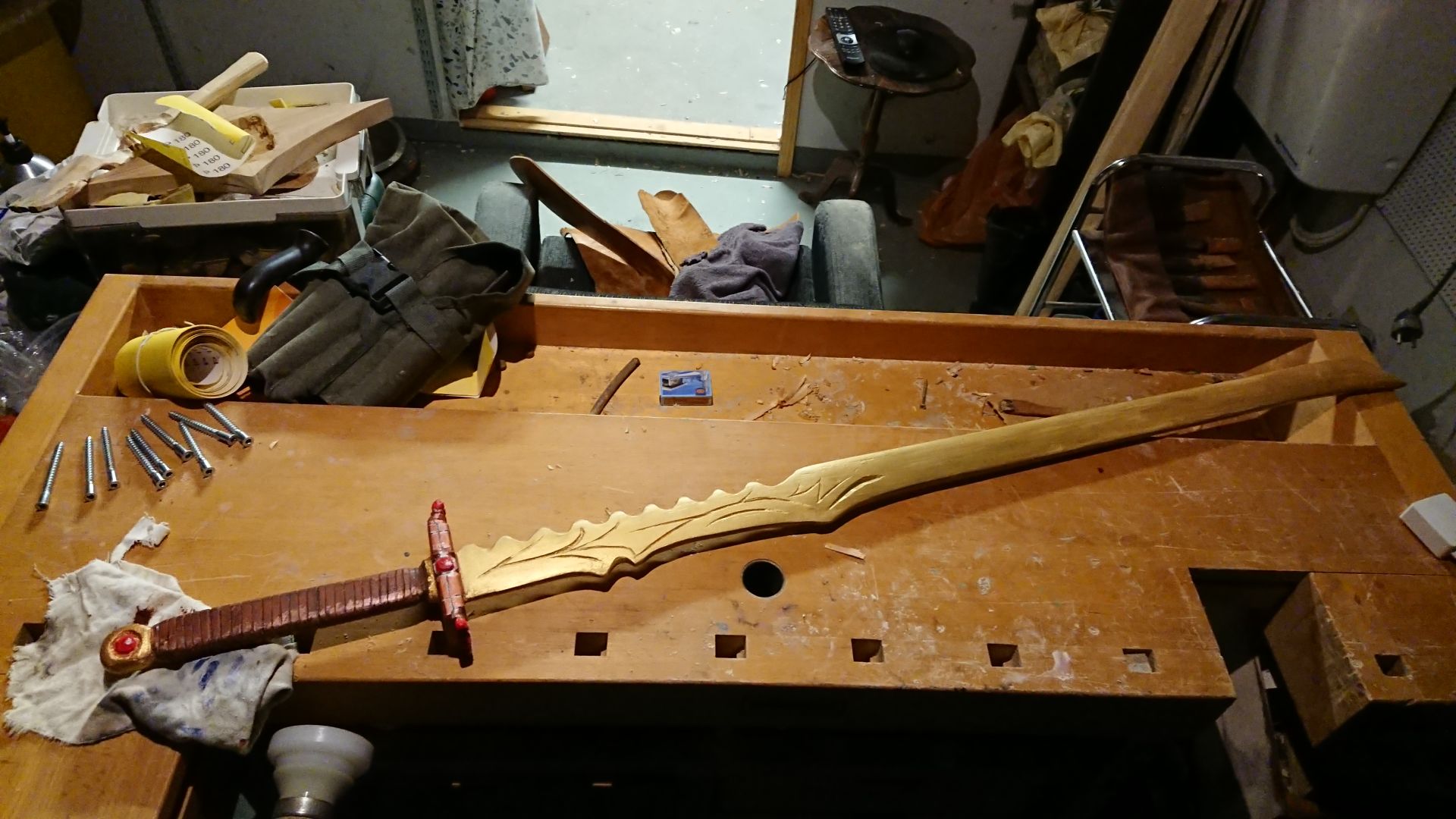 wooden sword. red/brown handle. gold blade. on workbench