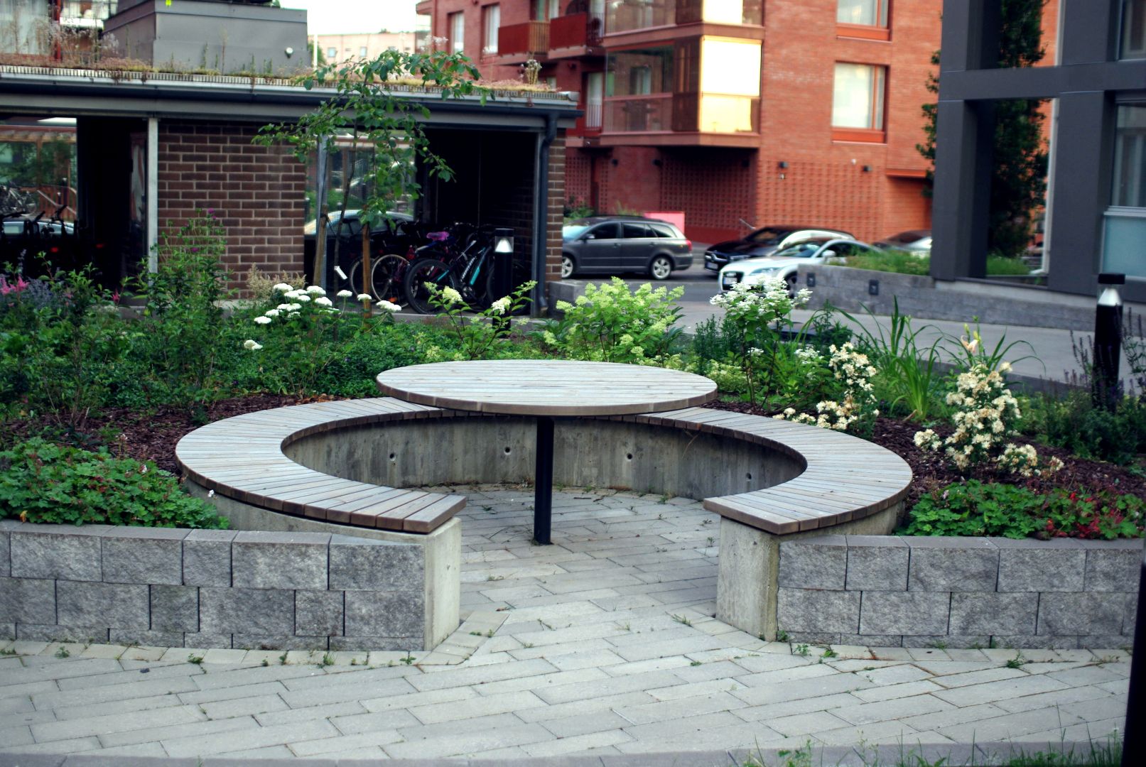 Pöytäryhmä istutusalueen sisällä pensaiden ympäröimänä.