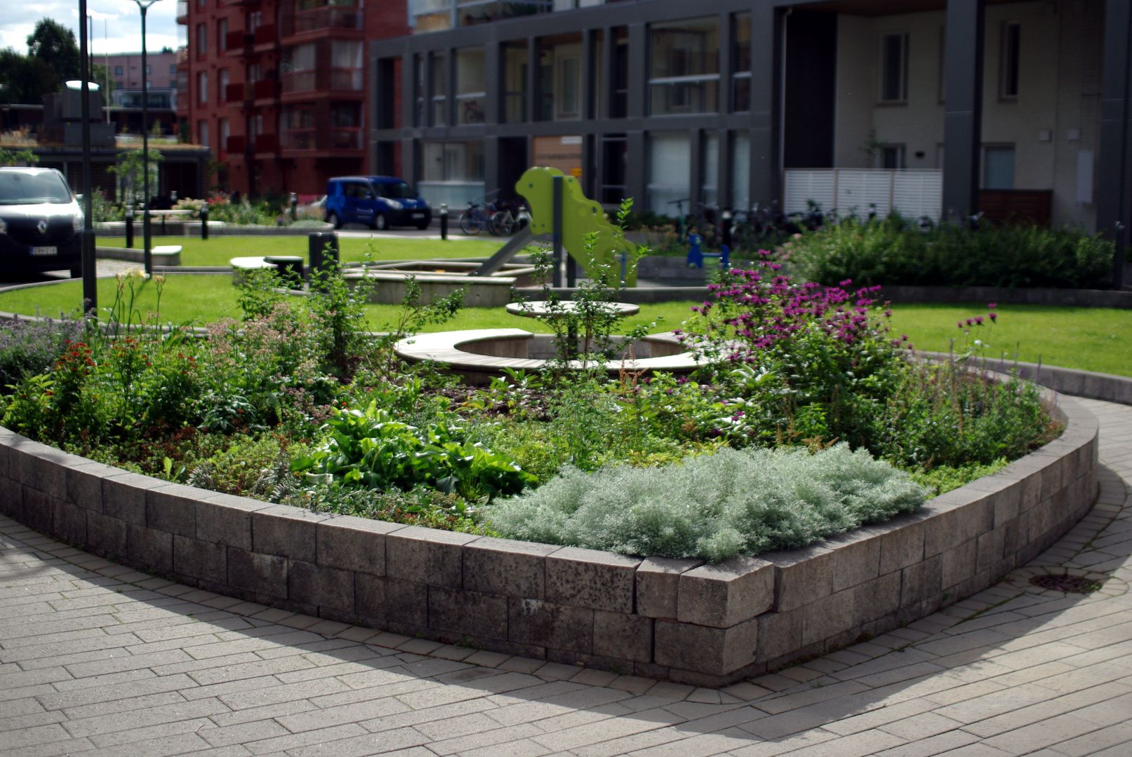 Vehreä ja kukkiva istutusalue, jossa runsaasti erilaisia perennoja.